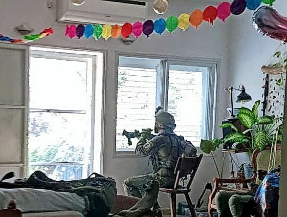 An IDF soldier keeps watch at the Ades family home after they survived the Oct. 7 terrorist attack on their kibbutz in Kfar Aza. The soldier helped the family celebrate their 5-year-old son Shir's birthday.