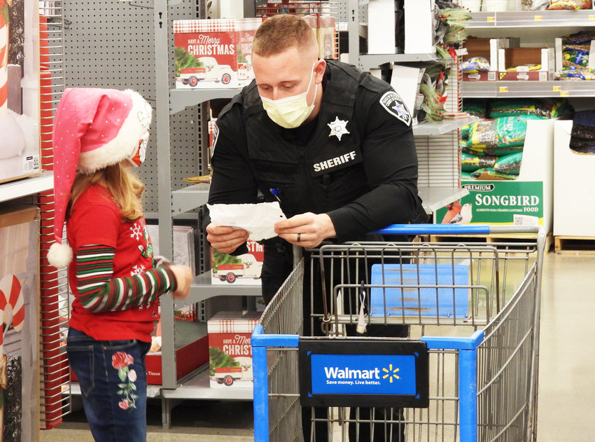 A FULL LIST &mdash; Eight-year-old Sophia Hanley goes over her Christmas list with a sheriff&rsquo;s deputy at the fourth annual Shop with a Sheriff event.