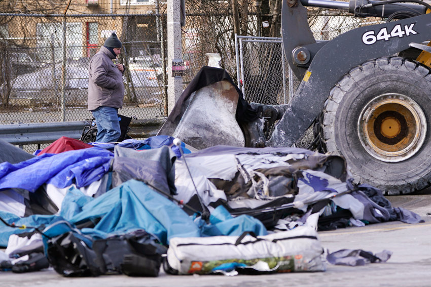 CLEANING UP &mdash; A City of Boston worker watches as a front-end loader scoops up tents, furniture and other items as a homeless encampment is cleared from the street Wednesdayin Boston. Boston Mayor Michelle Wu's made good on a self-imposed deadline to move people living in a homeless camp off the streets and into housing.