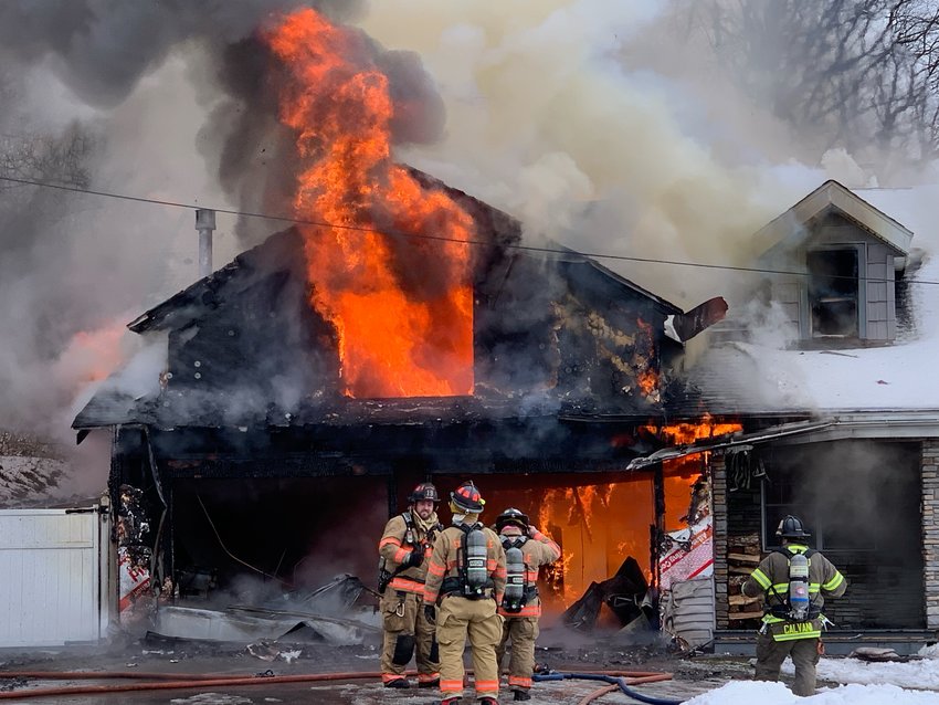 Bright orange flames engulf the garage at 8522 Chaminade Road in Marcy Friday afternoon while firefighters struggle to get water. Fire officials said they lost water pressure on the first hydrant they tried and had to find a second before hose lines could start fighting.