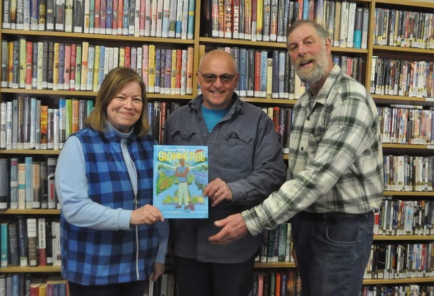GROWING IN POPULARITY &mdash; Agricultural Literacy Week book selection &quot;Will Allen and the Growing Table&quot; is presented to Cindy McVoy, Holland Patent Librarian, left,  by New York Farm Bureau President David Fisher, center, along with Oneida County Farm Bureau member Benjamin Simons.