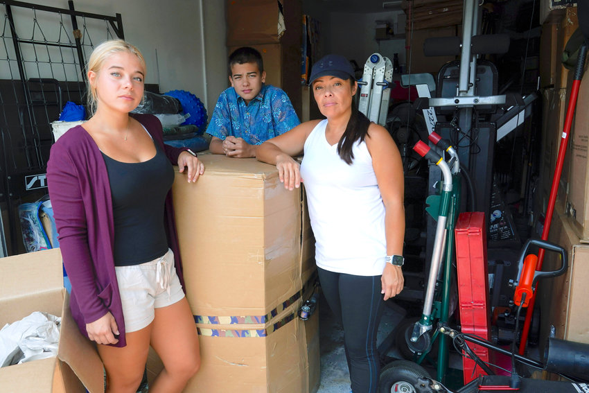 TIGHT SPOT &mdash; Wendy Kaufman stands at the entrance to her packed garage with her daughter Jaedyn, 19, and son Julian, 14, Tuesday, April 12, in Doral, Fla. The Kaufman&rsquo;s moved from Germany and have been unable to find a home big enough that they can afford.