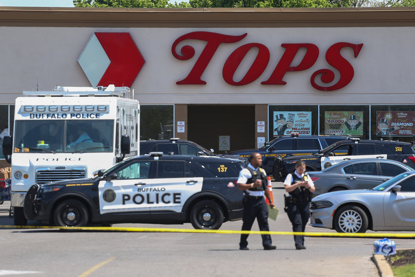 Police walk outside the Tops grocery store on Sunday, May 15, 2022, in Buffalo, N.Y. A white 18-year-old wearing military gear and livestreaming with a helmet camera opened fire with a rifle at the supermarket, killing and wounding people in what authorities described as &ldquo;racially motivated violent extremism.&rdquo;