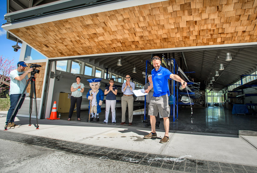 Hamilton College Head Rowing Coach Jim Lister christens the new Hamilton College Boathouse on Saturday, May 14, while city and college officials &mdash; and Alex, the Continentals mascot, look on.  (Photo courtesy Hamilton College/Nancy L. Ford)