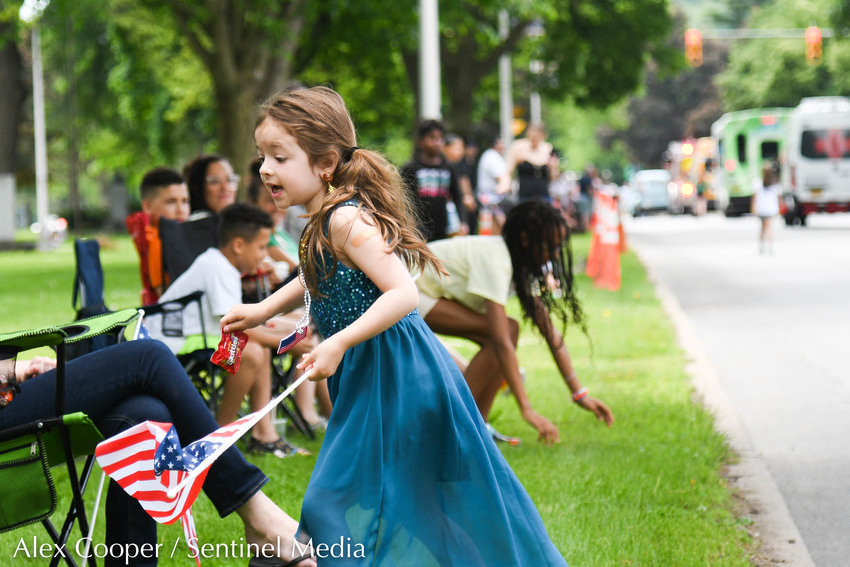 Lyra Williams chases candy while holding an American flag during Utica's annual Memorial Day Parade on Monday. The parade started on Genesee Street in front of St. Elizabeth Hospital, continued north on Genesee Street and then east on the Memorial Parkway; ending at the Parkway Recreation Center.