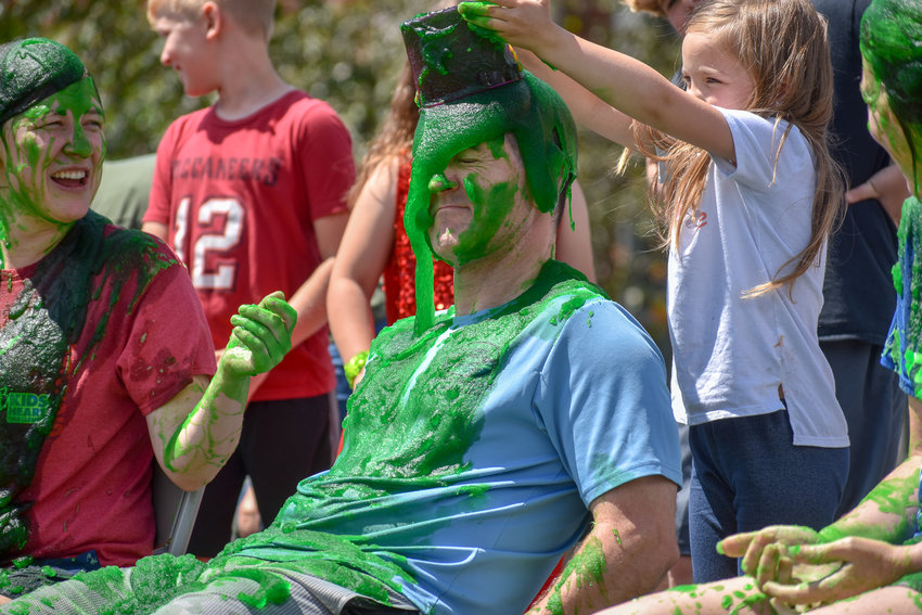 Madison Central School District Superintendent Jason Mitchell gets a bucket of green slime poured on his head by a student.