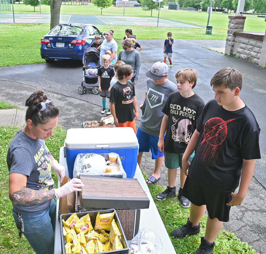 Rome City School District employee Hillary Young serves free sandwiches and sides to children lined up at Franklyn&rsquo;s Field on North James Street as part of the district&rsquo;s 2022 Summer Food Service program. Similar programs elsewhere in the county, including Utica, help ensure that local youths receive nutritious lunches even when school&rsquo;s not in session.