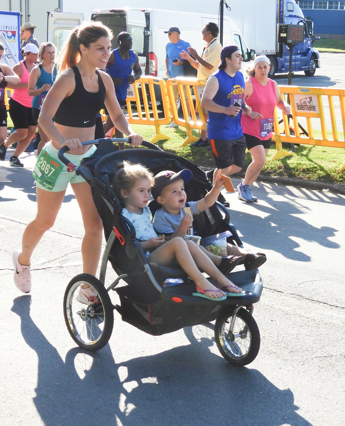 Audrieanna Raciti of New York Mills pushes a pair of the youngest participants in the Boilermaker 15K Road Race Sunday in Utica.