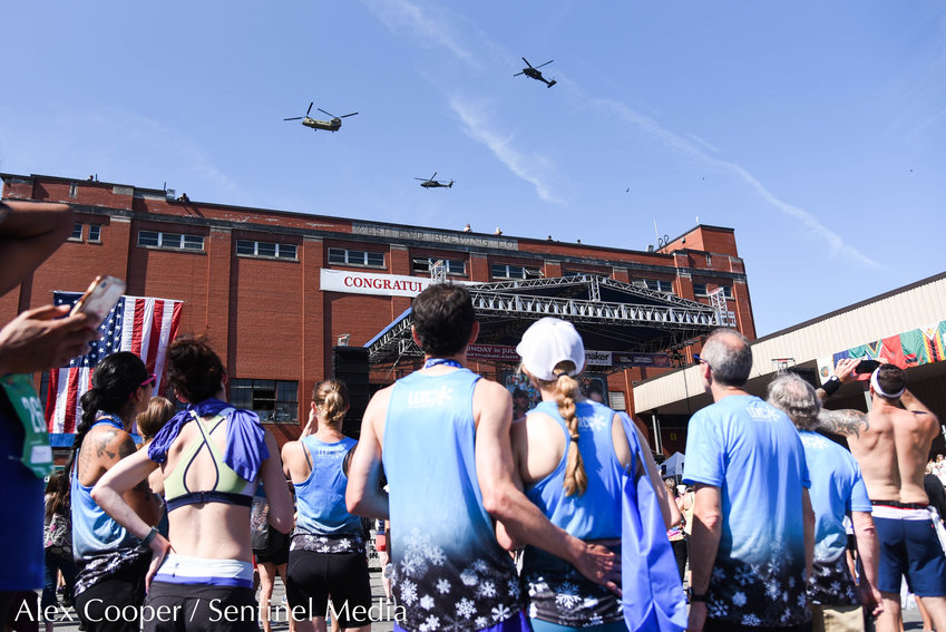 Runners watch a flyover at the Saranac Post Race Party following the 45th Boilermaker Road Race in Utica.