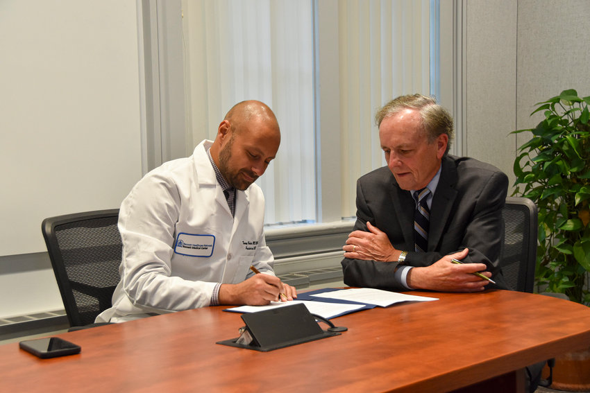 Dr. Tommy Ibrahim, Bassett Healthcare Network&rsquo;s president and chief executive officer, left, and Doug Hastings, Bassett Healthcare Network&rsquo;s Board of Directors chair, talk while Ibrahim signs a contract extension to continue to lead the network through 2029.