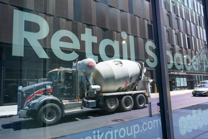 A cement mixer truck is reflected on a window advertising retail space for rent at a residential and commercial building under construction at the Essex Crossing development on the Lower East Side of Manhattan, Thursday.