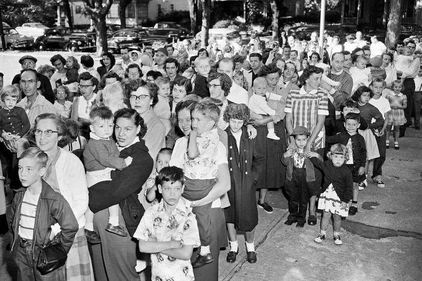 Parents and children wait outside the Riverside Public School in Elmira in this July 1, 1953 file photo, to get the polio vaccine, due to the rise in infantile paralysis in Chemung and Steuben counties. The Centers for Disease Control and Prevention said the polio virus was detected in wastewater samples collected in June 2022 from Rockland County outside New York City. An unvaccinated adult recently contracted the life-threatening disease, but health officials said Tuesday, Aug. 2, 2022, they have not identified additional cases.