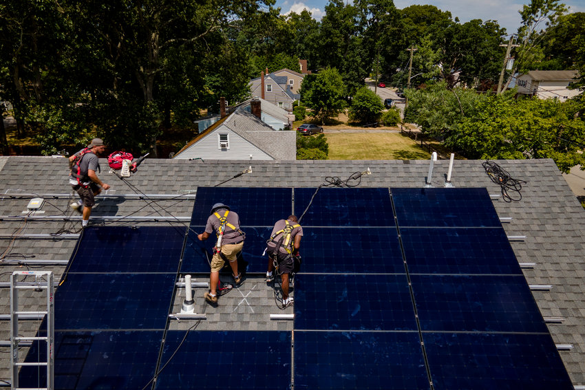 Employees of NY State Solar, a residential and commercial photovoltaic systems company, install an array of solar panels on a roof, Thursday, Aug. 11, 2022, in the Long Island hamlet of Massapequa, N.Y.  Americans are less concerned now about how climate change might impact them personally &mdash; and about how their personal choices affect the climate than they were three years ago, according to a according to a June poll from The Associated Press-NORC Center for Public Affairs Research.