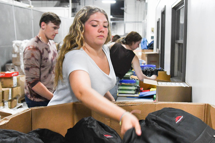 Samantha Williams helps fill backpacks with school supplies on Monday, Aug. 15 in a hangar located near Griffiss International Airport in Rome.