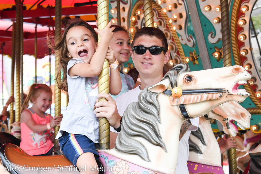 From left, Ellie Durr and her sister Evelyn Durr ride the carousel with their dad Joe Durr on Thursday at the Herkimer County Fair in Frankfort.