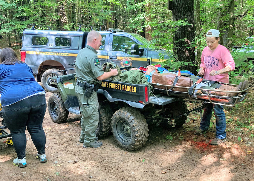 A state forest ranger and other rescue personnel helps a woman who was thrown off a horse near Otter Creek. She had to be rescued from the horse riding trails deep in the woods.