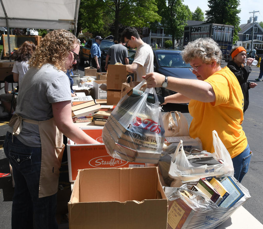 Missy Graves, right, delivers a bag of books as Jervis Public Library Executive Director Lisa Matte sorts through piles of books already dropped off at a previous recycling event at the library.