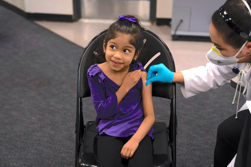 Elsa Estrada, then 6, smiles at her mother as pharmacist Sylvia Uong applies an alcohol swab to her arm before administering the Pfizer COVID-19 vaccine at a pediatric vaccine clinic for children ages 5 to 11 in Santa Ana, Calif., Nov. 9, 2021.