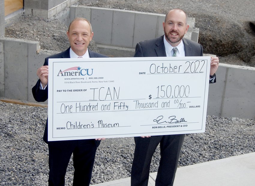 Ron Belle, left, AmeriCU president and CEO, and Steven Bulger, executive director and CEO of ICAN, pose with a ceremonial check to highlight AmeriCU&rsquo;s commitment of $150,000 toward the construction and development of the new $14 million Family Resource Center at 106 Memorial Parkway in Utica.