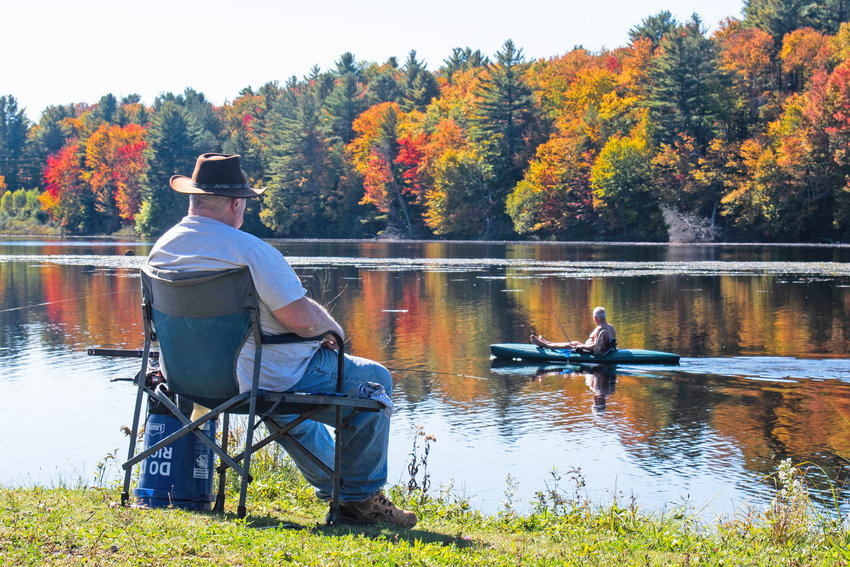 A kayaker paddles by as a man fishes at Forestport Reservoir on Wednesday, Oct. 5. According to observers with the state I LOVE NY fall foliage program, leaves are expected to be at peak color and brilliance in and around Old Forge this weekend with varying color shows elsewhere in the region.