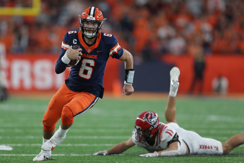 Syracuse quarterback Garrett Shrader, left, evades a tackle by North Carolina State linebacker Payton Wilson during the second half of an ACC game on Saturday in Syracuse.