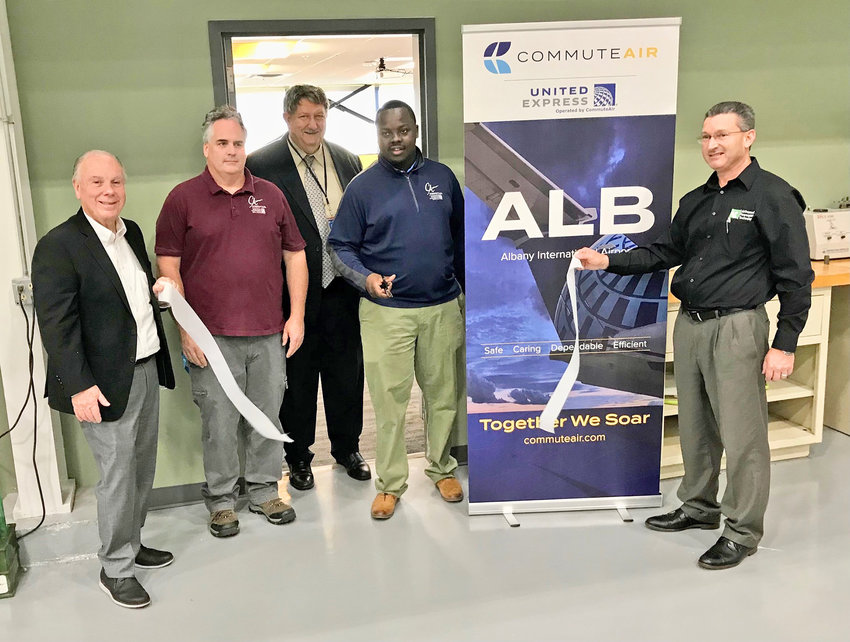 Mohawk Valley Community College and CommuteAir representatives including, from left, Frank DuRoss, Jim Connor, Lon Ziegler, Kwasi Bandoh and Walt Constantini cut the ribbon Wednesday to commemorate the opening of the new aviation maintenance classroom at the MVCC Aviation Training Center in Rome.