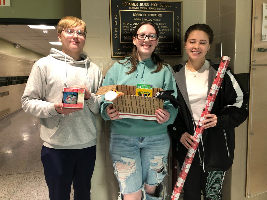 Herkimer Central School District National Junior Honor Society President Brian Flint, left, along with National Honor Society President Lilliana Langdon and Student Council President Izabella Vredenburg pose with items for the annual holiday project.(Photo submitted)