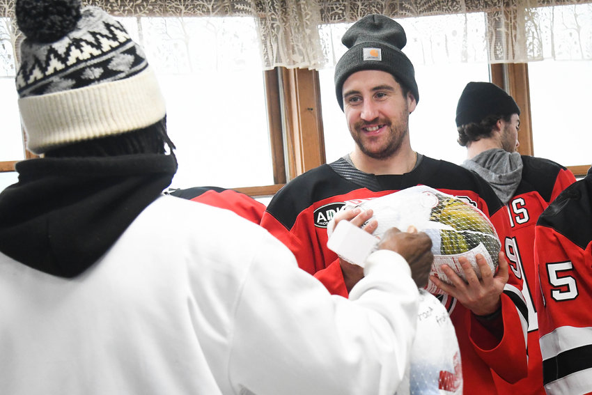 Utica Comets player Nick Hutchison helps hand out a turkey on Tuesday at the Utica Rescue Mission on Rutger Street. Players gathered to hand out turkey and other Thanksgiving food items to those in need, which is something the Comets have done in other seasons.