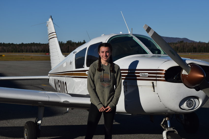 Sixteen-year-old Abigail VanDorn smiles next to an airplane after her first solo flight earlier this month at the Adirondack Regional Airport in Lake Clear.
