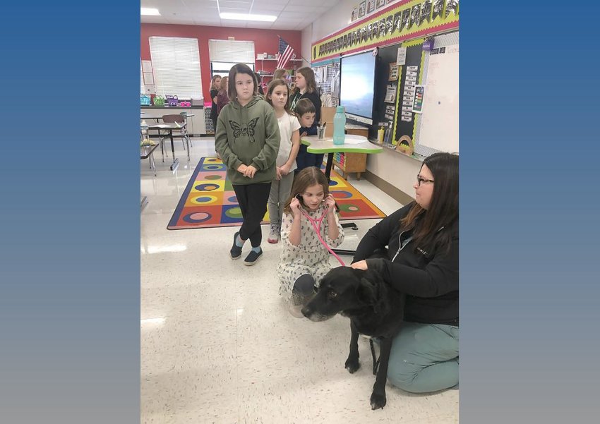 Herkimer Elementary School students visit with Amanda Mroz, right, a veterinary technician at Herkimer Veterinary Associates and a dog Nov. 16 during the school&rsquo;s Career Day.