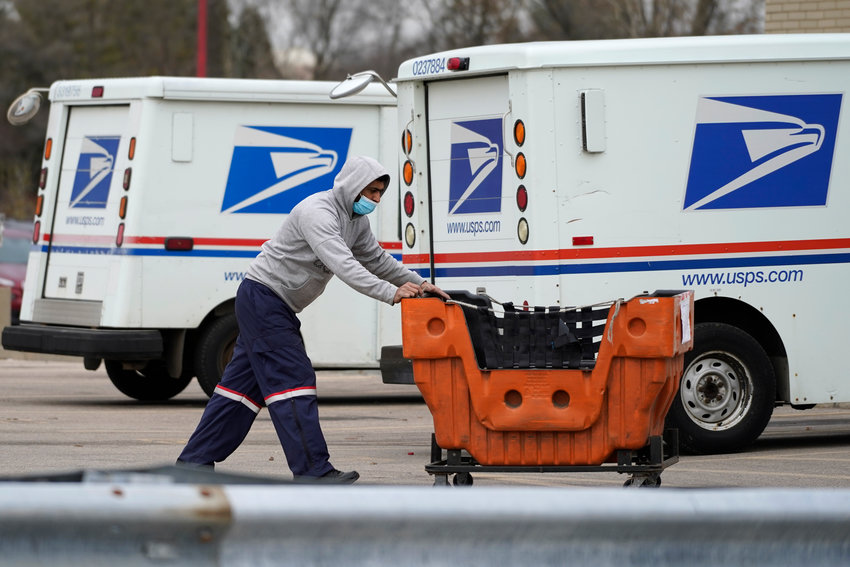 A United States Postal Service employee works outside a post office in Wheeling, Ill., in this 2021 file photo. The nation's major shipping companies are in the best shape to get holiday shoppers&rsquo; packages delivered on time since the start of the pandemic, suggesting a return to normalcy.