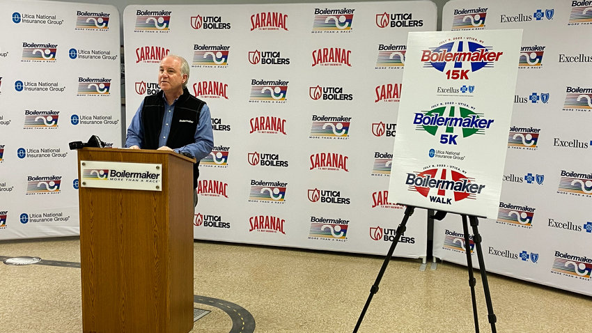 Boilermaker Road Race President Mark Donovan alongside the new logos unveiled for the 2023 Boilermaker Weekend events.
