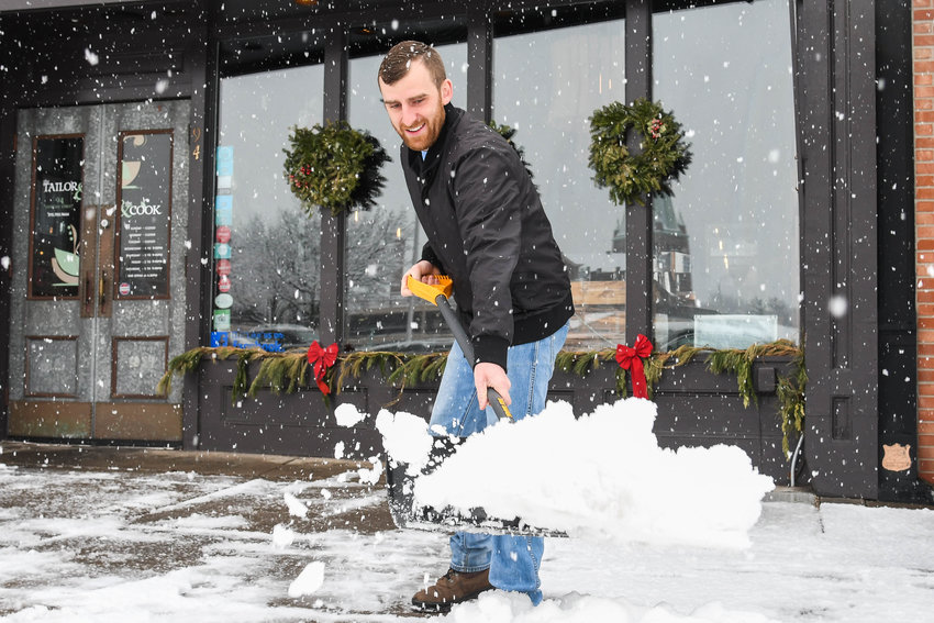 Patrick Zenon shovels snow in front of The Taylor and the Cook restaurant on Friday, Dec. 16 in Utica.