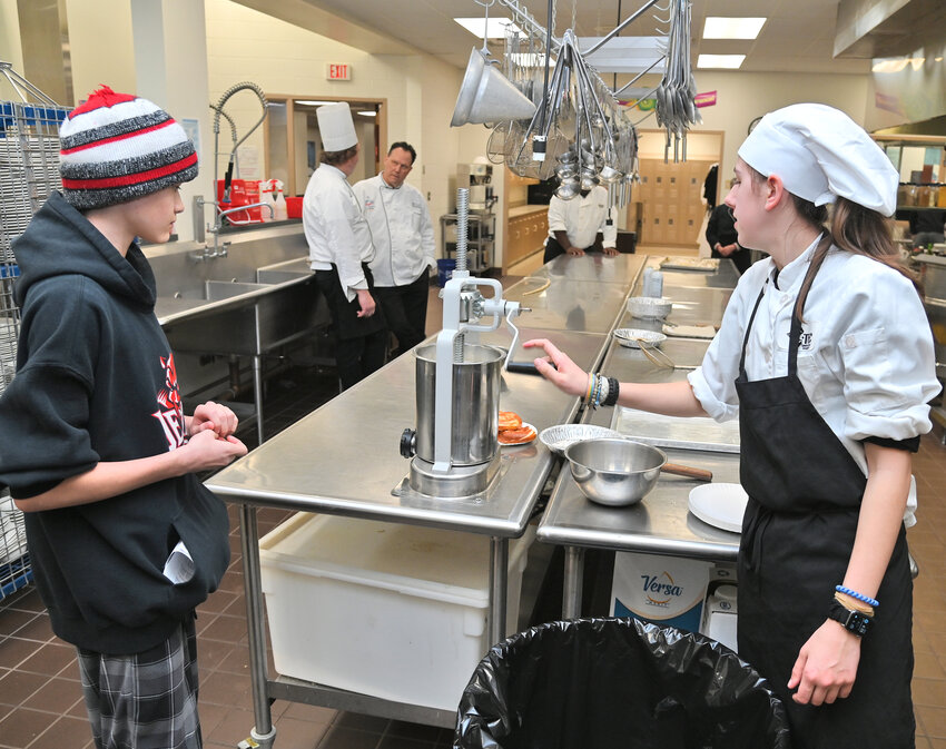 OHM BOCES culinary student Isabella Aceto, right, demonstrates a meat press to VVS ninth grader Alexander Ayala during the CTE open house Wednesday in New Hartford.