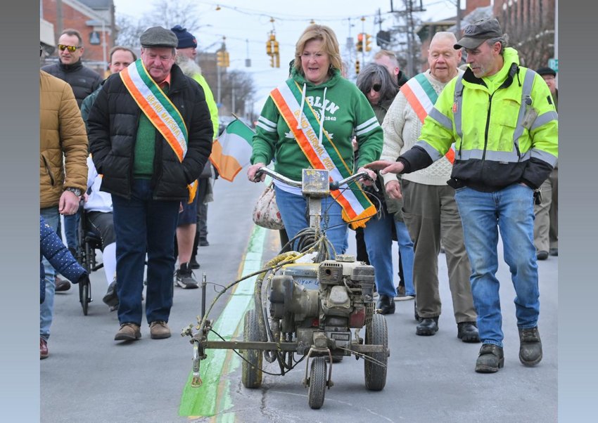 Colleen Kain Martin, grand marshal of Utica&rsquo;s St. Patrick&rsquo;s Day parade, runs the line striper with the help of George Sabo, a maintenance tech for the City of Utica, as the green center line is painted along Genesee Street for today&rsquo;s parade. The official color of the line is Kelly Green. Today&rsquo;s parade begins at 10 a.m. at Oneida Square and will travel northbound along Genesee Street to Columbia Street.
