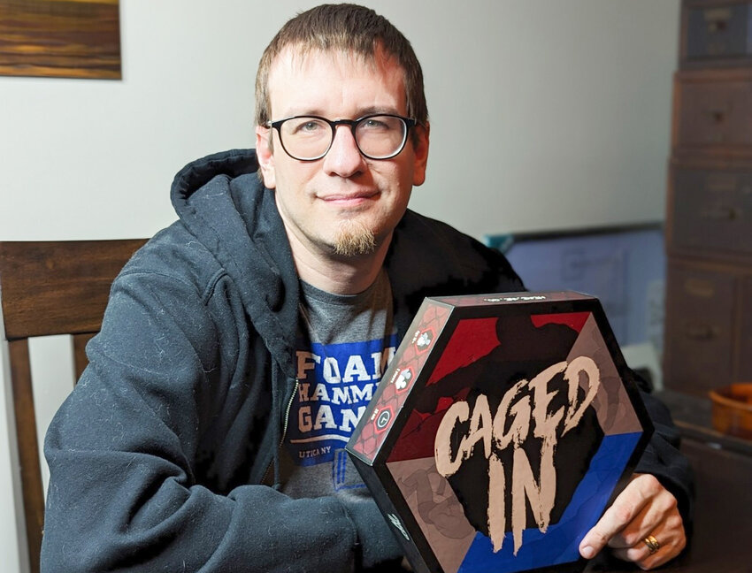 Paul LaPorte, owner of Foam Hammer Games, holds a copy of Caged In.