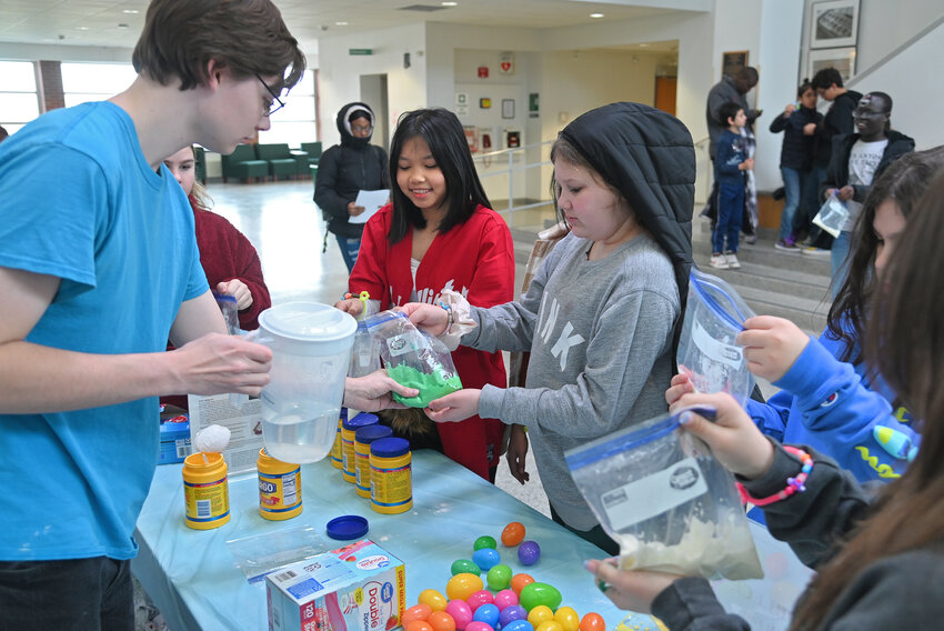 Brandon Massett, a second year student at MVCC in the physics and engineering science program, left, helps students from Ann Reiben&rsquo;s sixth grade class at Columbus Elementary School make Oobleck Friday, March 24 during STEM Fest in Wilcox Hall.