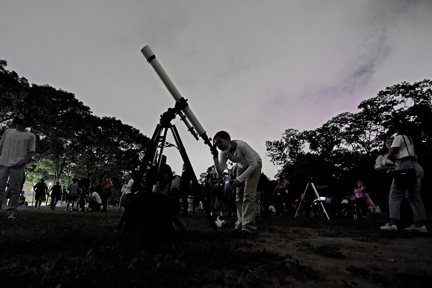 A girl looks at the moon through a telescope in Caracas, Venezuela, on Sunday, May 15, 2022. The best day to spot five planets, Mercury, Jupiter, Venus, Uranus and Mars, lined up in the night sky is Tuesday, March 28, right after sunset. The five-planet array will be visible from anywhere on Earth, as long as you have clear skies.