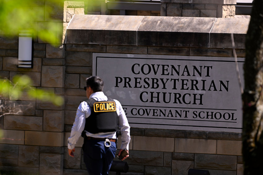 A police officer walks by an entrance to The Covenant School after a shooting in Nashville, Tenn. on Monday, March 27, 2023.