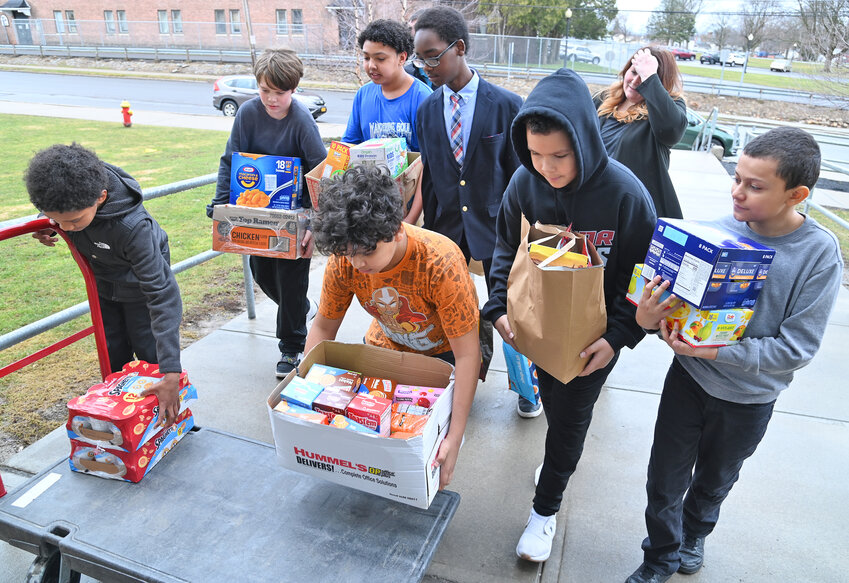 Kernan Elementary School students, from left, Rahkeem Gilmore, Hayden Noon, Amyed Alzanam, Zamiere Williams, Nuer Gaw, Ivan Toldeo and Javario Roman bring food to a hand truck that was delivered by MVCC student support advisors and Community Outreach Committee members Robin Saxe and Daniel Eddy.