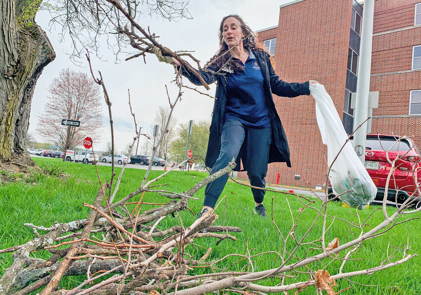 Rome Health CEO AnneMarie Walker-Czyz clears sticks and other debris from around the hospital grounds on the morning of Earth Day on Saturday. She was joined by 30 staff and family members, who cleaned up more than 36 bags worth of trash.