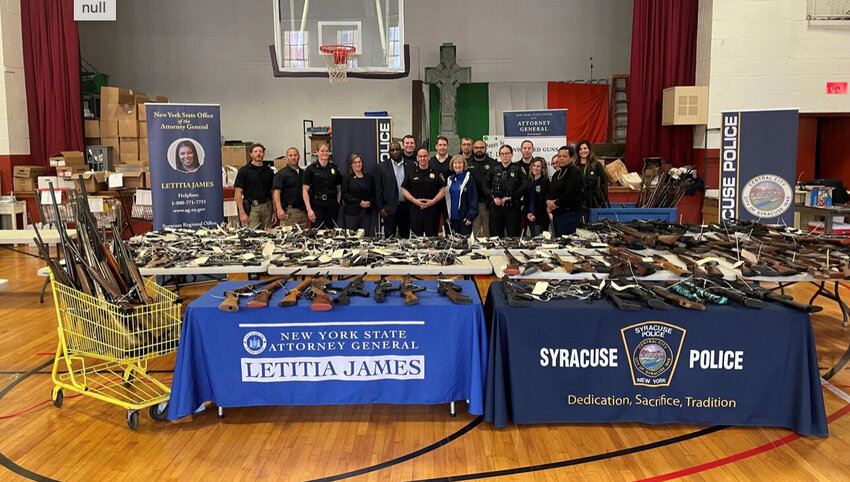Law enforcers as well as state and local officials show guns collected during a buyback event in Syracuse on Saturday.