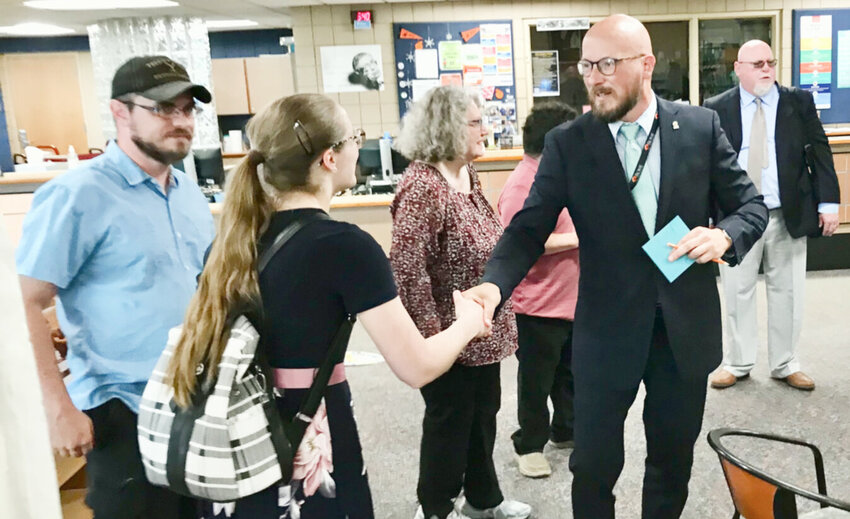 Rome City School District Superintendent Peter Blake, right, congratulates newly tenured English teacher Susan Mills while her husband Taylor Mills, left, watches Monday, May 22 before the board of education meeting in the Rome Free Academy library.
