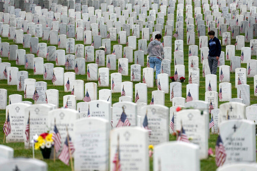 People walk among the headstones as they visit Section 60 at Arlington National Cemetery on Memorial Day, Monday, May 29, 2023, in Arlington, Va.