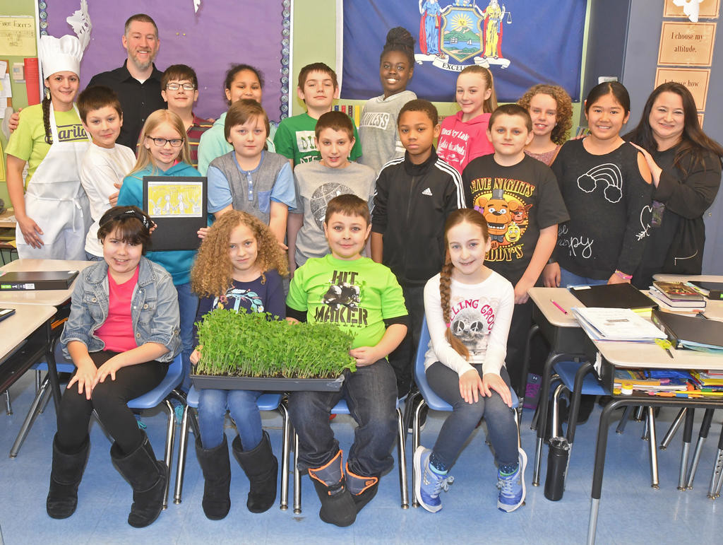 FINAL PRODUCT — Scott Royce and his fifth grade class at Bellamy Elementary School show off one of their beds of micro greens sweet peas today on harvest day. With them are Sarita Ruiz, back row left, and Christina Carambia, back row right. Carambia proposed the program and brought along Ruiz, who runs Sarita's Food Truck, to explain how she prefers local, natural ingredients.
 (Sentinel photo by John Clifford)