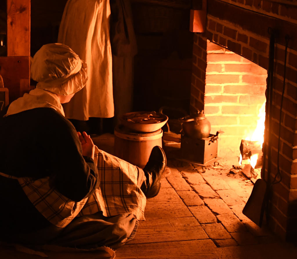 HOME IS WHERE THE HEARTH IS — Kierstin Bratge keeps warm by the fire in the German Room at Fort Stanwix National Monument on Saturday night. Dozens of historic re-enactors gathered to share what the holidays were like in the Mohawk Valley during the 18th century as part of Fort Stanwix’s annual Holiday Open House.  The fort will be available for holiday viewing through the end of November. A schedule of events for 2018 will be posted soon at Fort Stanwix’s website: www.nps.gov/fost.
 (Sentinel photo by John Clifford)