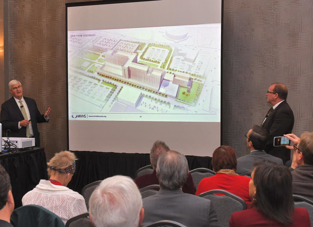 HERE’S THE PLAN — Robert Scholefield, left, chief operating officer at the Mohawk Valley Health System, and Kim Way, principal of architectural design firm NBBJ, explain the new images of the proposed downtown Utica hospital Thursday. The external design of the building is not finalized, they noted, but will reflect the functions inside the building.
 (Sentinel photos by John Clifford)