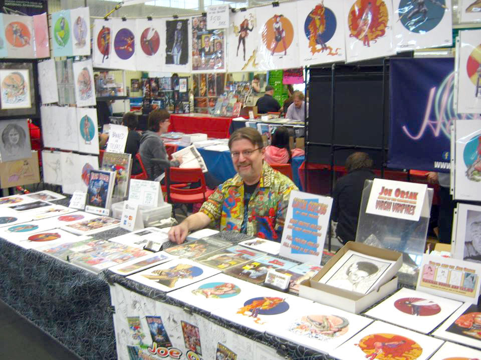 LOCAL ARTIST — Syracuse-based artist Joe Orsak surrounds himself with his superhero artwork at Uticon.
 (Photo submitted)