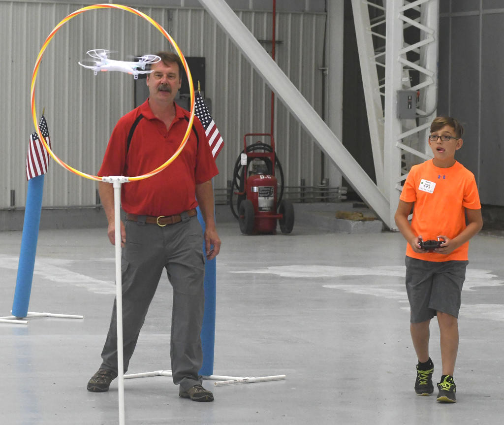 FLYING THORUGH HOOPS — Michael Matzek, 13, of New Hartford, at right, directs his drone through part of an obstacle course this morning during a Drone 1.0 STEM (science, technology, engineering, math) Summer Camp program. At left is instructor Bill Judycki. Today’s activities, at the NUAIR nose dock at Griffiss airport, concluded the week-long camp which also included sessions at Mohawk Valley Community College in Utica.
 (Sentinel photo by John Clifford)