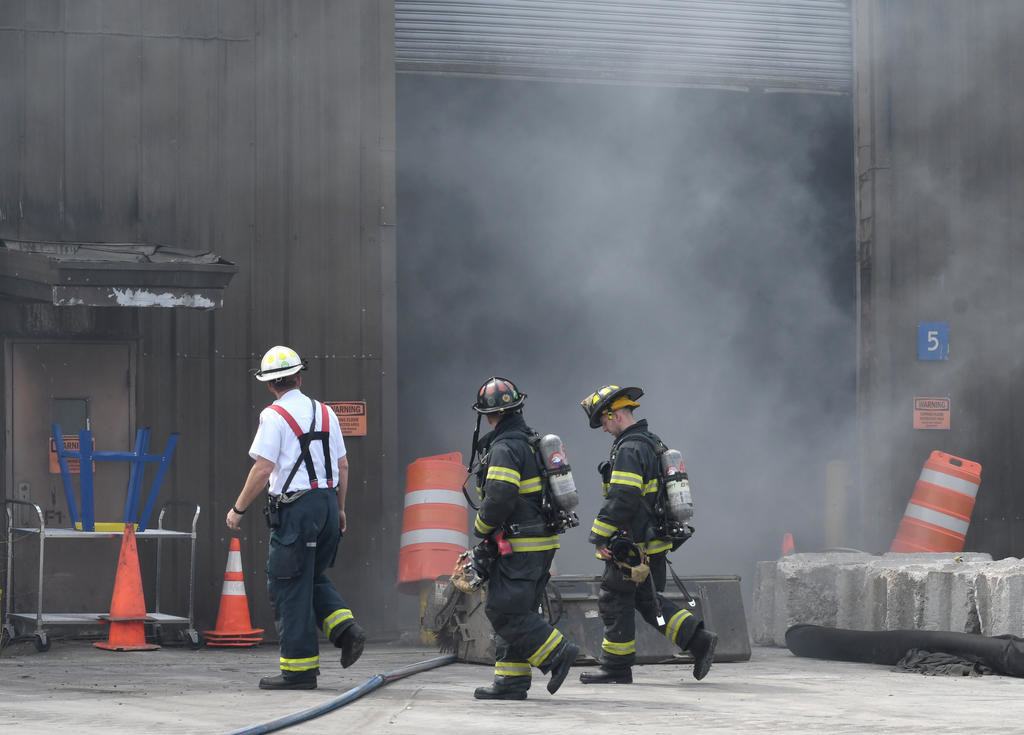 SMOKE ON THE GARBAGE — Deputy Fire Chief Mark S. Kohlbrenner, left, leads his firefighters around the smoke at the transfer station on Perimeter Road Thursday afternoon.
 (Sentinel photo by John Clifford)